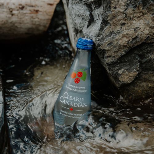 Clearly Canadian - Four 325ml Bottles of All Four Flavours On a Rock by a Mountain Stream