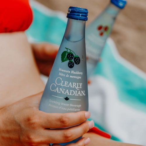 Clearly Canadian - Four 325ml Bottles of All Four Flavours On a Rock by a Mountain Stream
